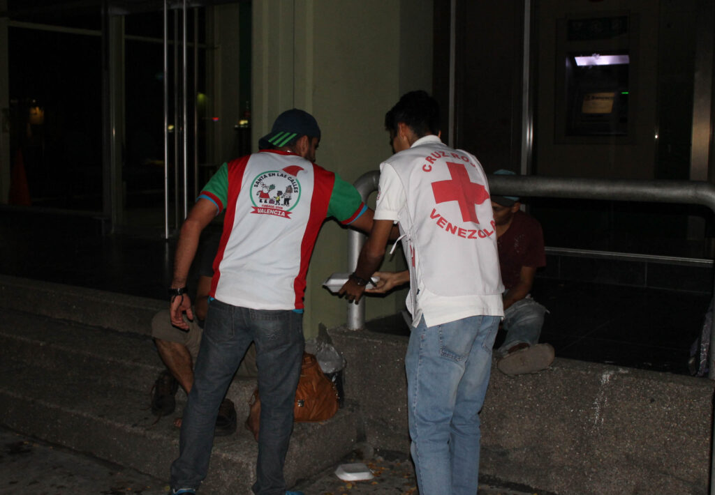 "Elfo" de la fundación entregando comida en colaboración con un miembro de la Cruz Roja de Venezuela. Foto: Santa en las Calles